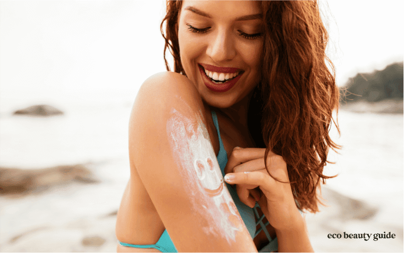 woman on beach making smile with sunscreen on arm
